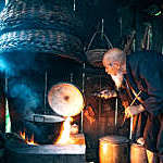 old chinese senior man cooking water in simple kitchen