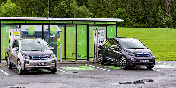 Bergen, Norway - Jule, 2016: EV Car or Electric car at charging station with the power cable supply plugged in on nature background. Charging modern electric car.