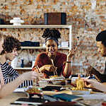 Young people sitting together at table having lunch break