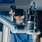 Close-up Shot of a Futuristic Robotic Arm Controlled by Professional Development Engineer with Virtual Reality Headset and Joysticks in a High Tech Research Laboratory with Modern Equipment